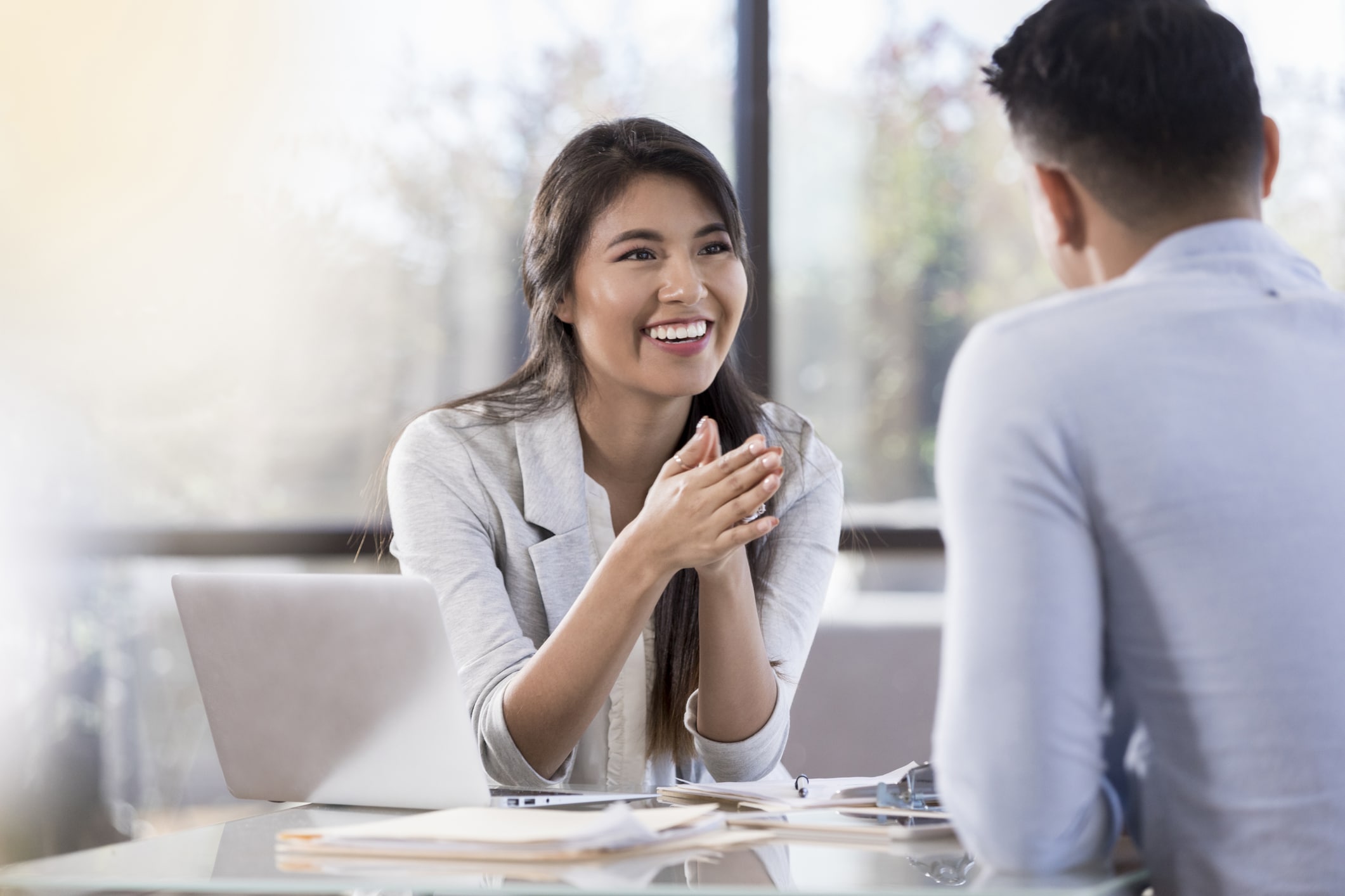 Smiling young Hispanic businesswoman meets with a male colleague.